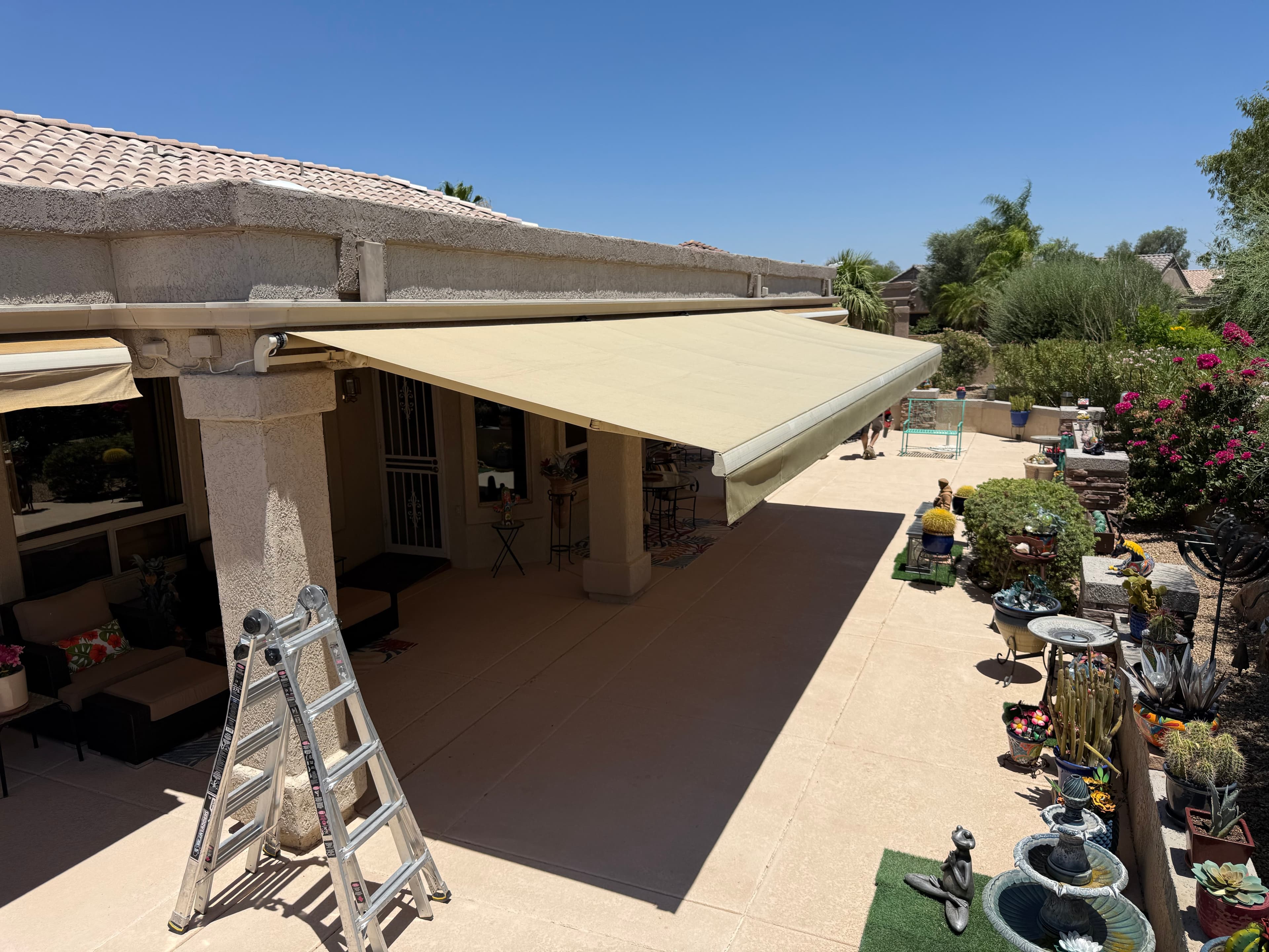 Retractable awning with newly recovered tan fabric shading a Phoenix patio